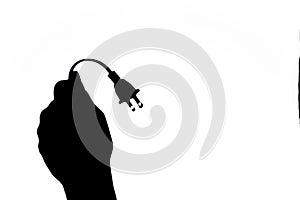 Silhouette image of a hand holding up a electric power cable and plug