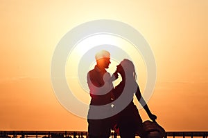 Silhouette image of a loving couple embracing at sunset on a lake.