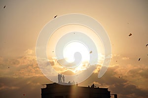 Silhouette image of people flying kites from house terrace in India