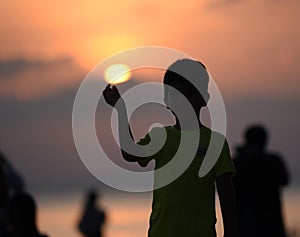 Silhouette image of young boy holding sun