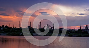 Silhouette of industrial factory at sunset mirror in water