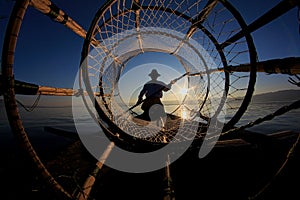 Silhouette of intha fisherman against the sunset sky