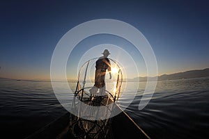 Silhouette of intha fisherman against the sunset sky