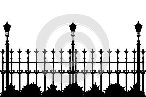Silhouette of iron fence with street flashlights and plants.