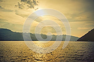 silhouette Island mountain in open water golden sunset sky reflection