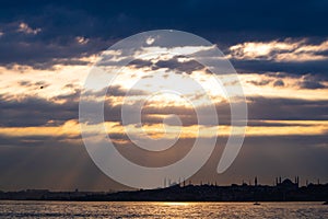 Silhouette of Istanbul at sunset with dramatic cloudy sky and sunlight beams. photo