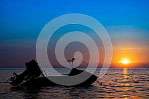 Silhouette of jetski floating on calm sea at sunset