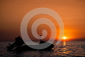 Silhouette of jetski floating on calm sea at sunset