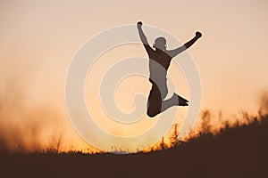 Silhouette of jumping man on sunset fiery sky