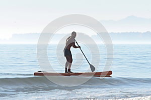 Silhouette of a kayaker on a personal rowing kayak, rowing a kayak with an oar in the sea at dawn