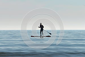 Silhouette of a kayaker on a personal rowing kayak, rowing a kayak with an oar in the sea at dawn