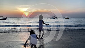 Silhouette of Kids playing in beach during sunset playing sand slow motion