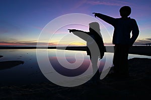 Silhouette of kids pointing in a beautiful sunset