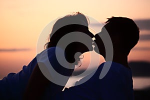 Silhouette kissing man and woman on beach