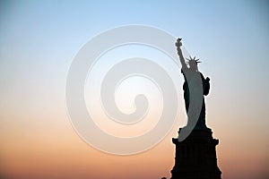 The silhouette of Lady Liberty during an epic summer sunset