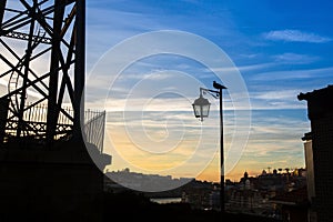 Silhouette of lamp with bird on background of the city and the twilight blue sky.clouds