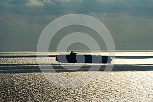 Silhouette of large container ship anchors in the sea