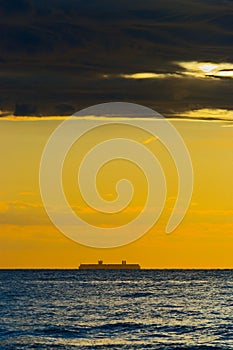 Silhouette of large container ship on the horizon.