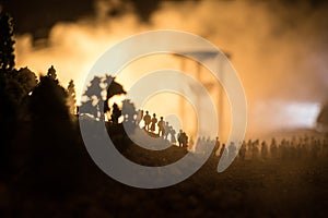 Silhouette of a large crowd of people in forest at night standing against a big hourglass with toned light beams on foggy backgrou