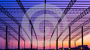 Silhouette of large factory building outline structure in construction site against colorful twilight sky background