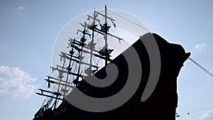 The silhouette of a large wooden ship with mast and sail against the sky