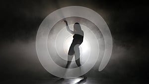 Silhouette leggy girl dancing in a smoky studio rhythmic dance