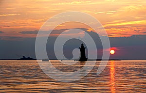 Silhouette of the lighthouse and boats during the sunset at Cape Henlopen State Park, Lewes, Delaware, U.S.A photo