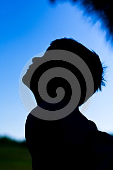 Silhouette of little boy against blue sky