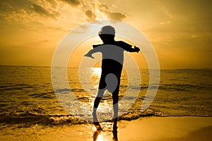 Silhouette of little boy jumping over the beach wave sunshine