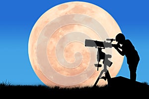 Silhouette of little boy looking through a telescope