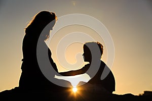 Silhouette of little boy touching pregnant mother tummy