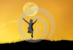 Silhouette little girl jumping to sky on sunset with full moon.