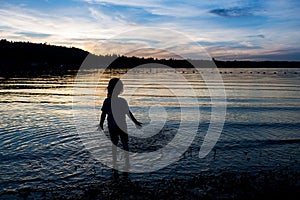 Silhouette of little girl playing in the water in twilight