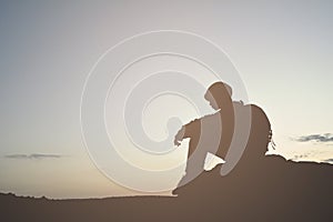 Silhouette of little girl waiting for sunset on top mountain