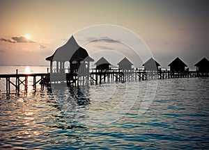 Silhouette of lodges in the sea at sunset. Maldives