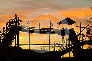 Silhouette of log flume ride retro style against golden sunset sky