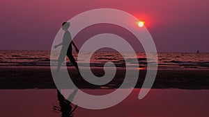 Silhouette. lonely asian young man walking peacefully along a deserted beach at sunset. seascape