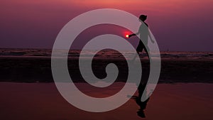 Silhouette. Lonely Asian young man walking peacefully along a deserted beach at sunset. Seascape