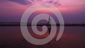 Silhouette. Lonely Asian young man walking peacefully along a deserted beach at sunset. Seascape