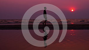 Silhouette. lonely asian young man walking peacefully along a deserted beach at sunset. seascape