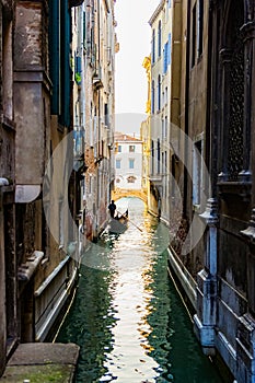 Silhouette of a lonely sad gondolier in a gondola without passengers in a narrow side channel in Venice, Italy. No people because