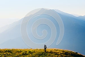Silhouette of a lonely traveler at sunrise against the background of a high mountain