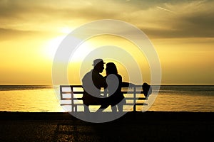 Silhouette of a loving couple on bench at sunset on the seashore