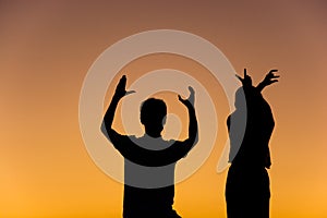 Silhouette of loving couple with hands in L,O,V,E shape