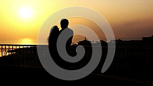 Silhouette Of A Loving Couple Hugging and Kissing Near the Sea on the Balcony at Sunset