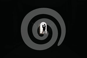 Silhouette of loving couple hugging while standing in doorway on black background, Bride and groom in wedding day posing in a