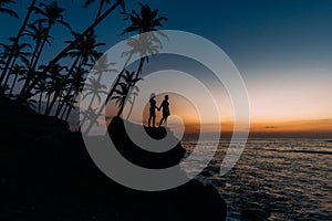 Silhouette of loving couple on sea. Man and woman at sunset. Honeymoon on the Islands. Man and woman meet sunset. Happy loving