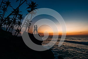 Silhouette of loving couple on sea. Man and woman at sunset. Honeymoon on the Islands. Man and woman meet sunset. Happy loving