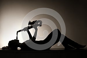 Silhouette of lying woman playing saxophone