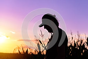 Silhouette of male farmer standing on cornfield